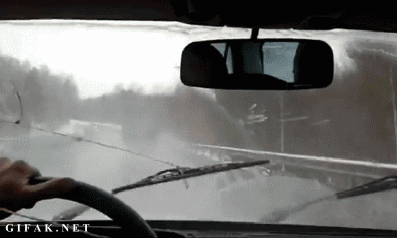 Animated GIF of person manually operating windscreen wipers from inside a car, illustrating the concept of repetitive manual work